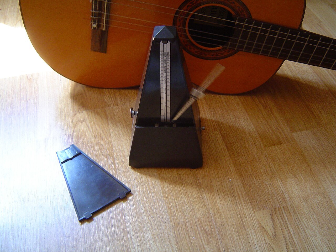Mechanical metronome beside a guitar.