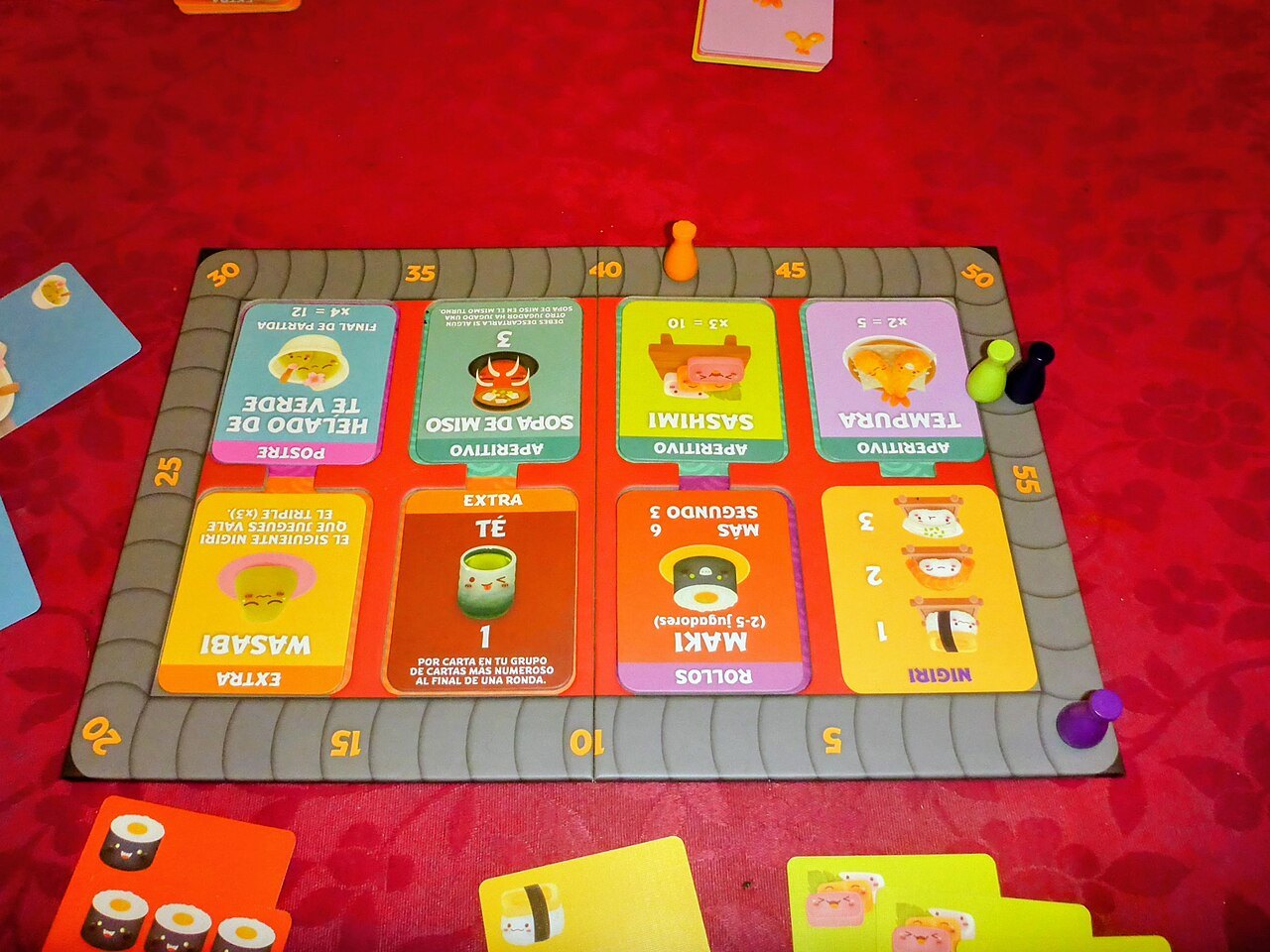 Cards and scoring board from Sushi Go Party laid out for play.