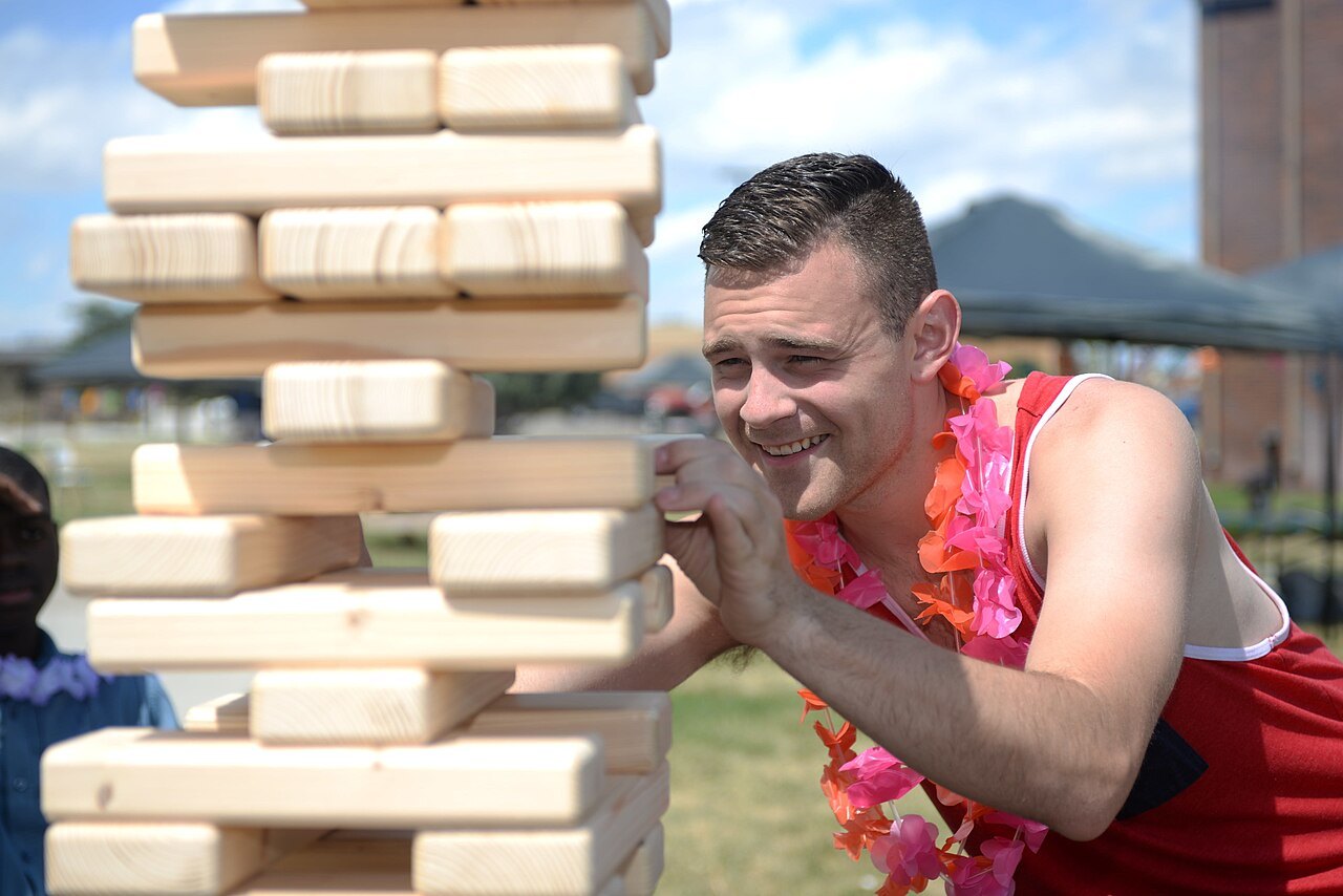 A player removes a block from a large wooden tower.