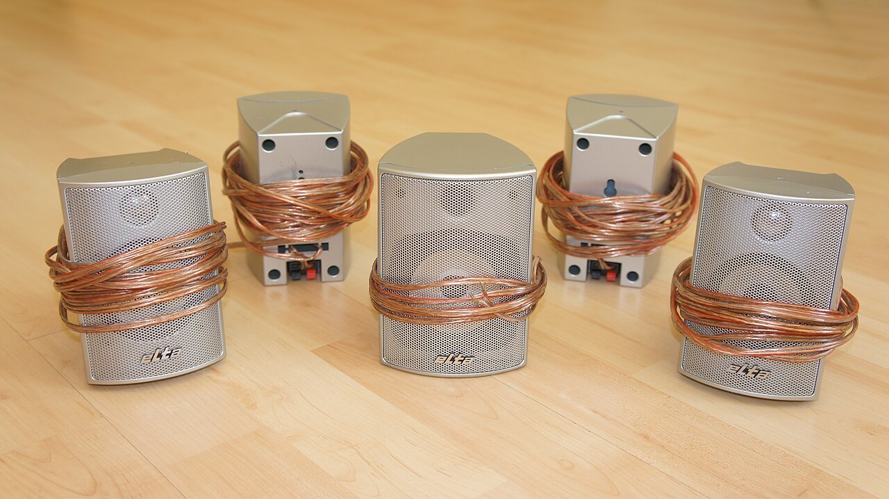 Five speakers from a surround set with connection cables.