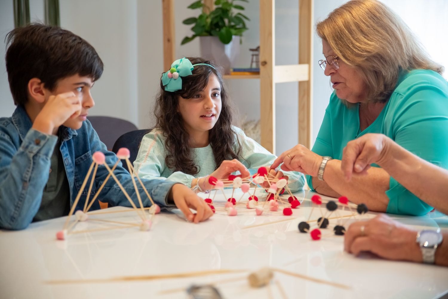 Children and older adults build together using rods and connectors.