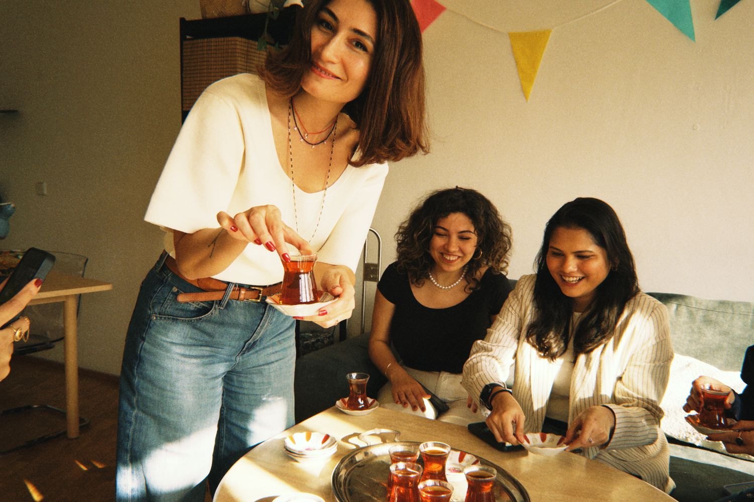 A small gathering with tea and pastries around a table.